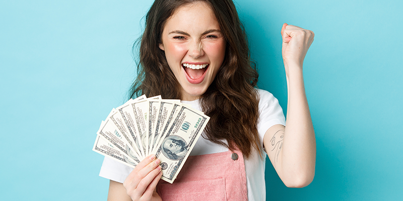 Woman holding dollar bills in her handed and celebrating